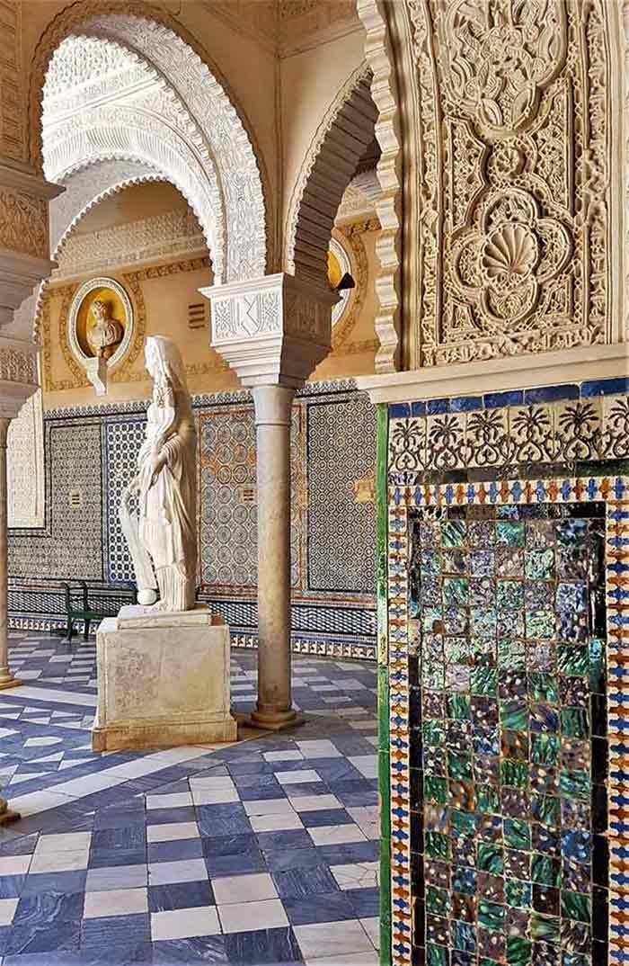 Casa de Pilatos with the decorative tiled walls and coluns with detailed palster work. Thre is a marble statue next to a column.