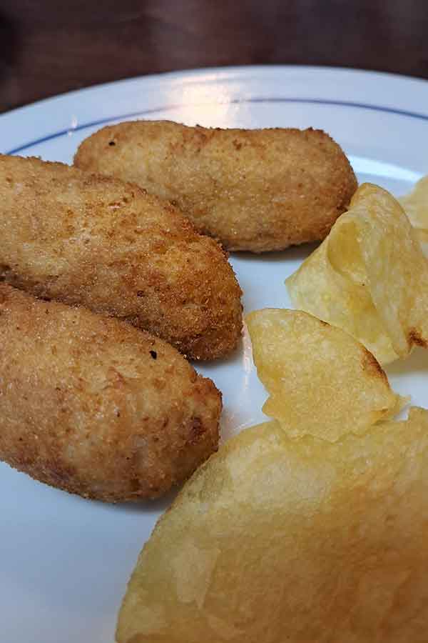 Croquetas de Jamon Three Croquetas de Jamon on a plate next to crisps