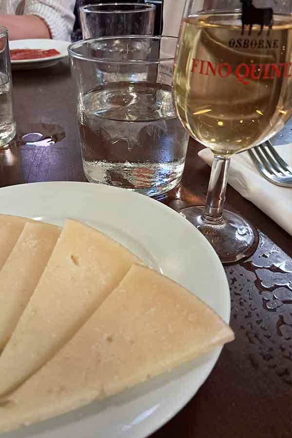 Manzanilla and Queso Viejo A glass of Manzanilla - a light yellowish coloured drink and a plate of Queso Viejo which is a cured cheese.