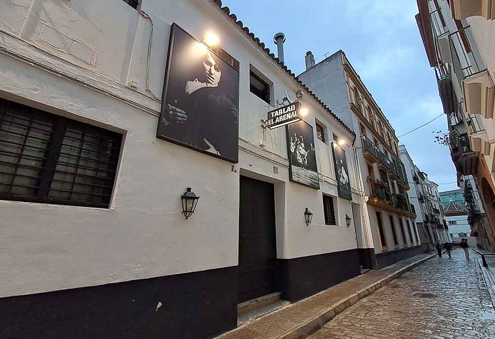 Tablao El Arenal Outside Tablao El Arenal with black and white photos of flamenco dancers and a black and white sign on the wall.