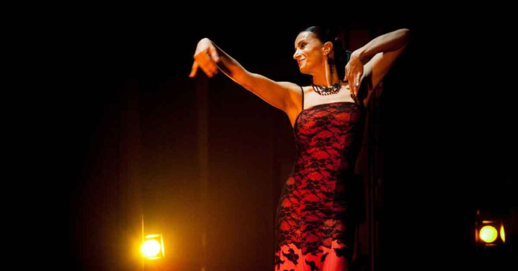 Dancer in a red and black lace dress. A lady wearing a red and black laced dress and dancing flamenco. This is the featured image for an article about where to find the best flamenco in Seville.