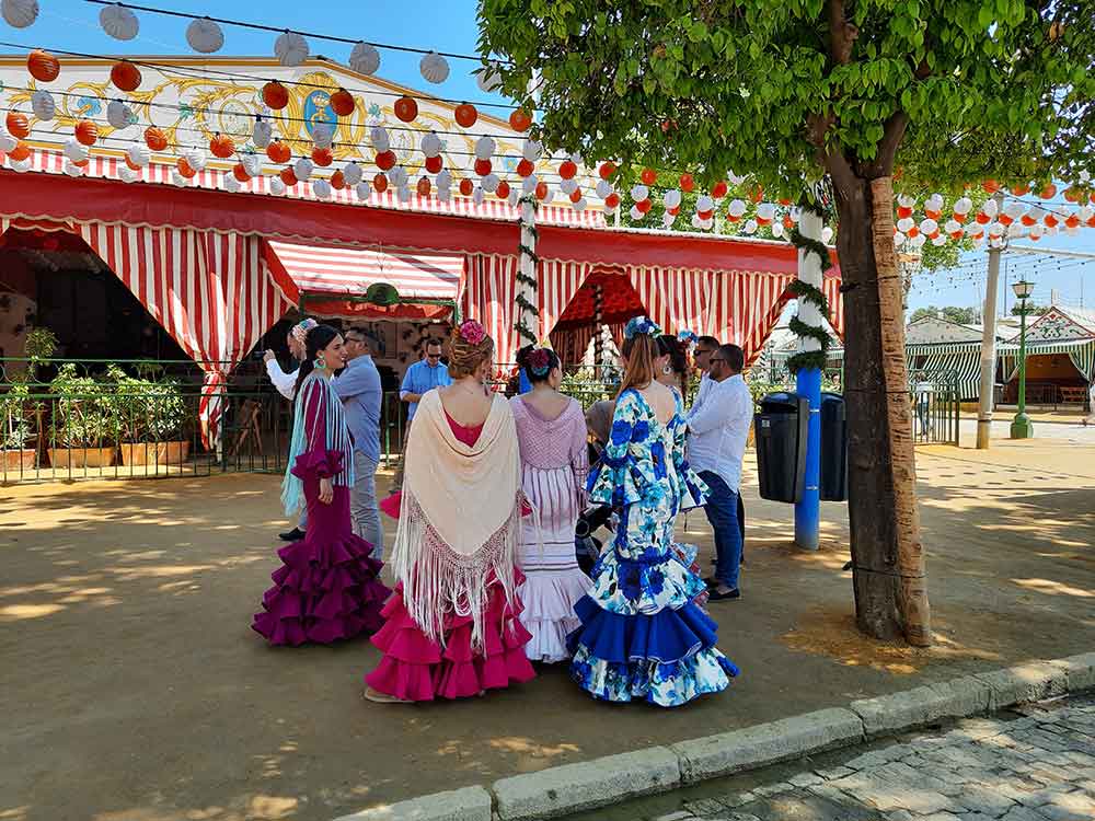 Women in flamenco dresses outside a caseta at Seville April Fair