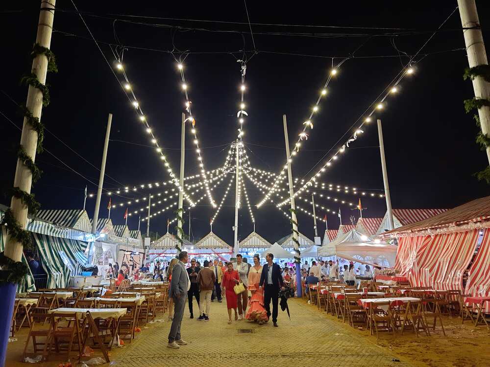 Visitors walking between illuminated casetas at the Seville April Fair