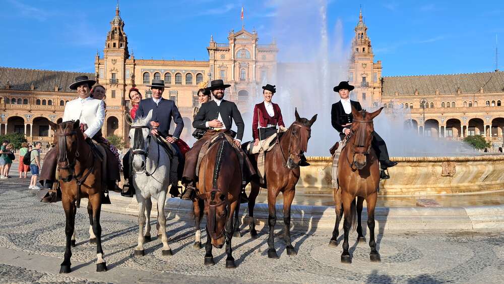 Men and women in equestrian Feria de Abril Seville outfits at Plaza de España
