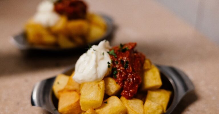 Patatas bravas topped with sauce, one of the classic tapas to try when exploring food in Seville.